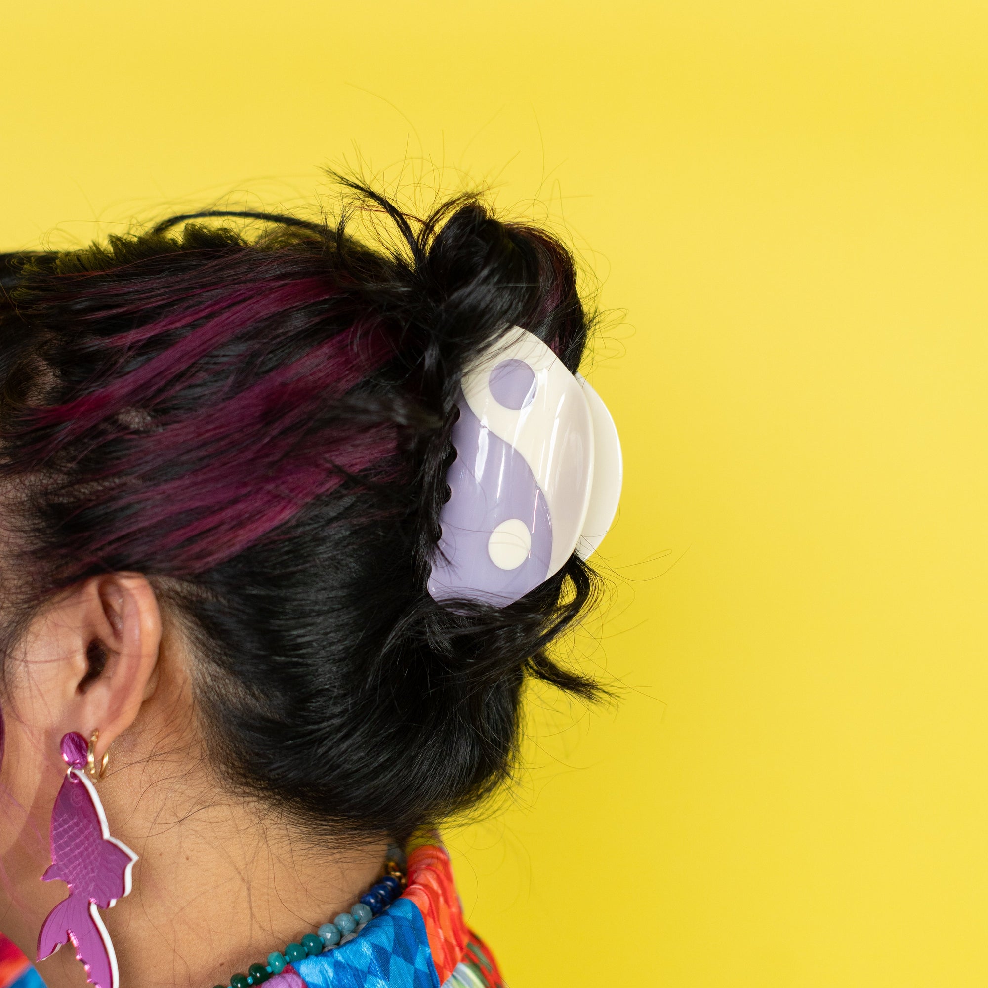 Person with colorful hair accessories against a yellow background