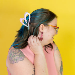 Person with blue hair and tattoos wearing a pink sleeveless top against a yellow background