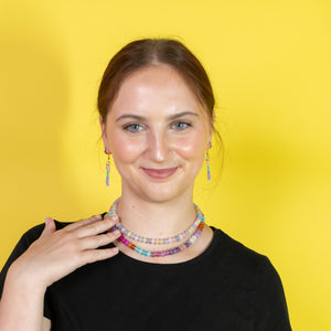 Woman wearing a colorful beaded necklace against a yellow background