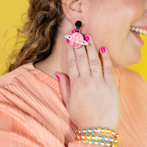 Woman wearing colorful earrings with a yellow background