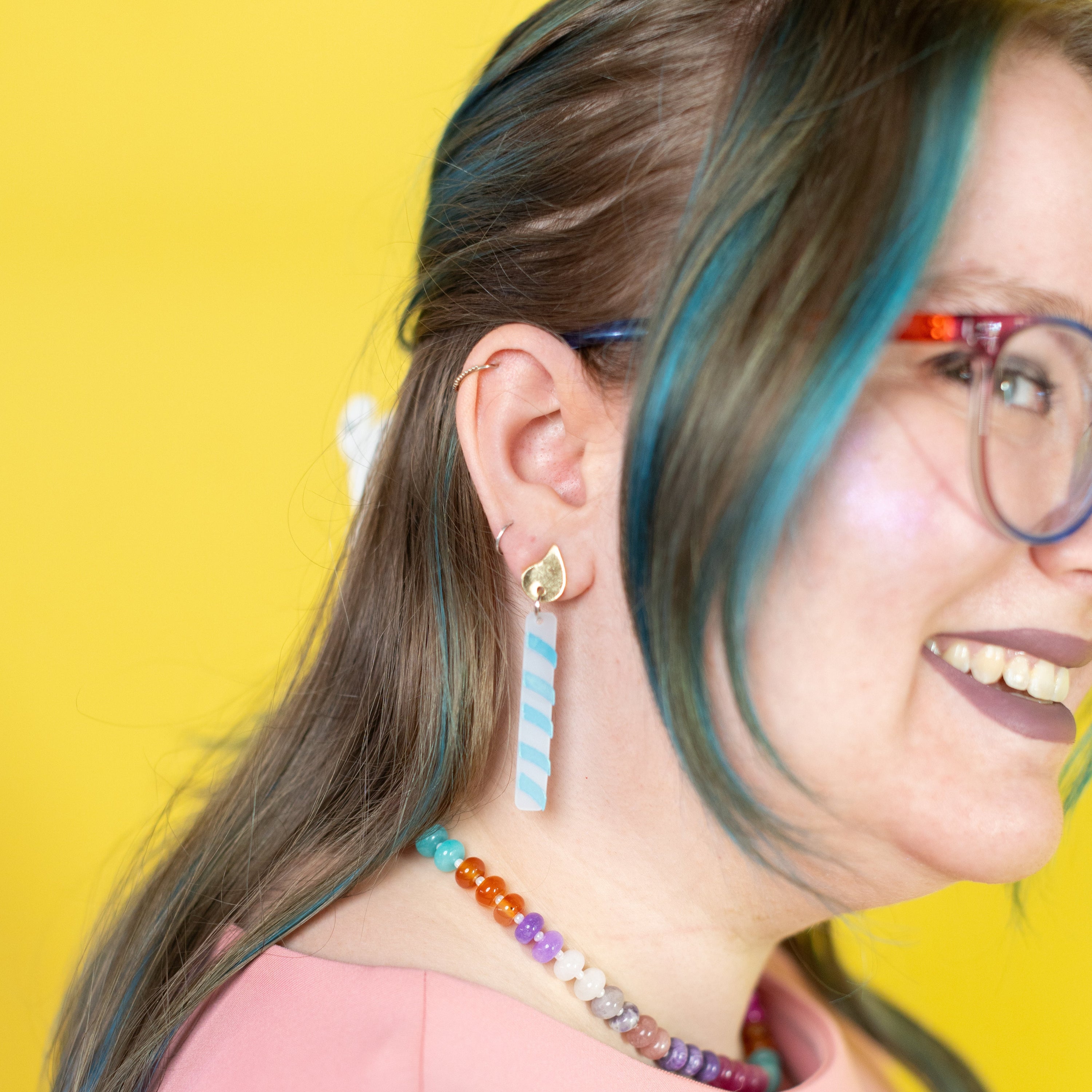 Person with colorful hair and accessories against a yellow background