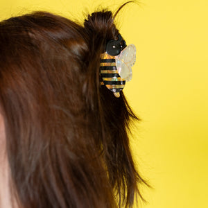 Close-up of a person's hair with a decorative hair clip against a yellow background