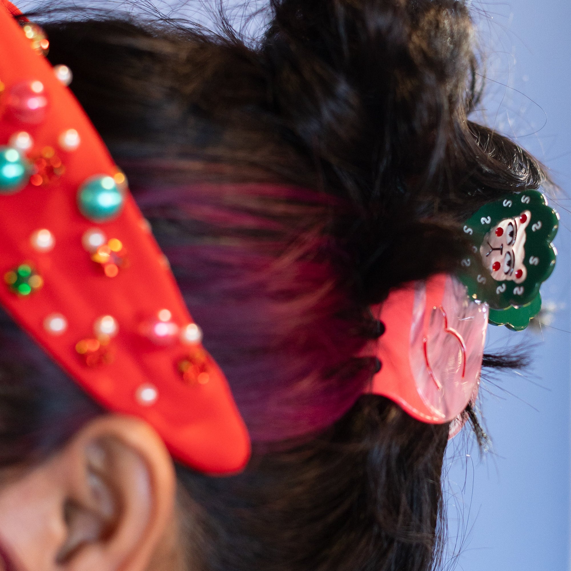 Close-up of a person's head with colorful hair accessories against a blue background
