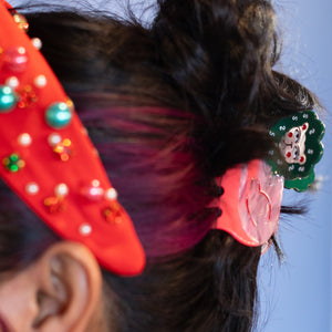 Close-up of a person's head with colorful hair accessories against a blue background