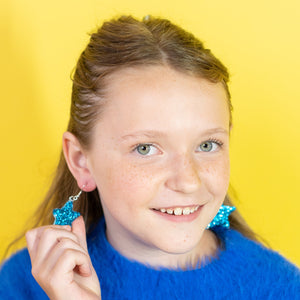 Young girl wearing a blue sweater against a yellow background