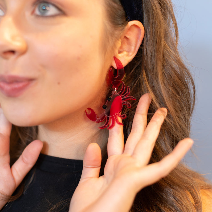 Woman wearing a black top and floral earrings against a light blue background