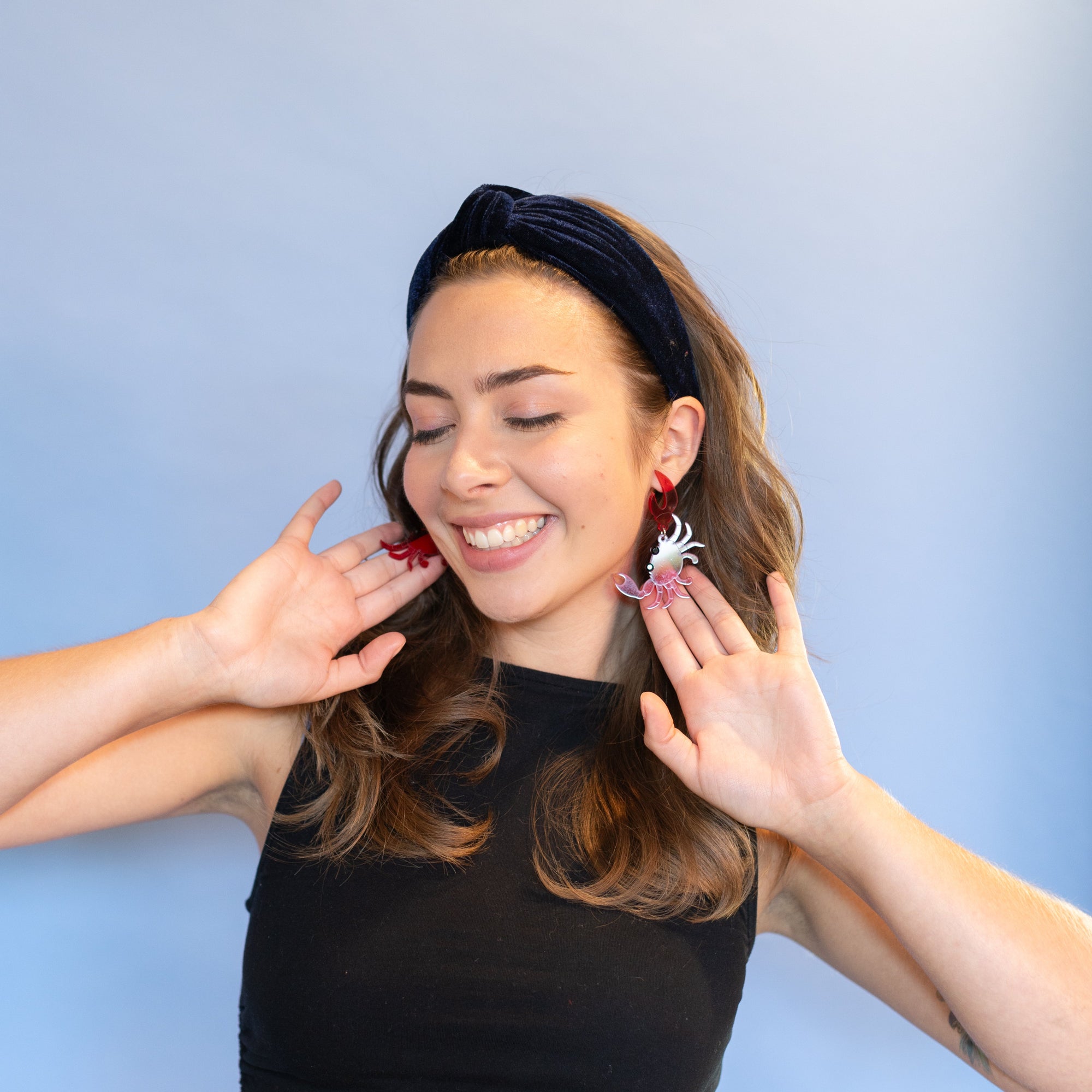 Woman wearing a black top and floral earrings against a light blue background