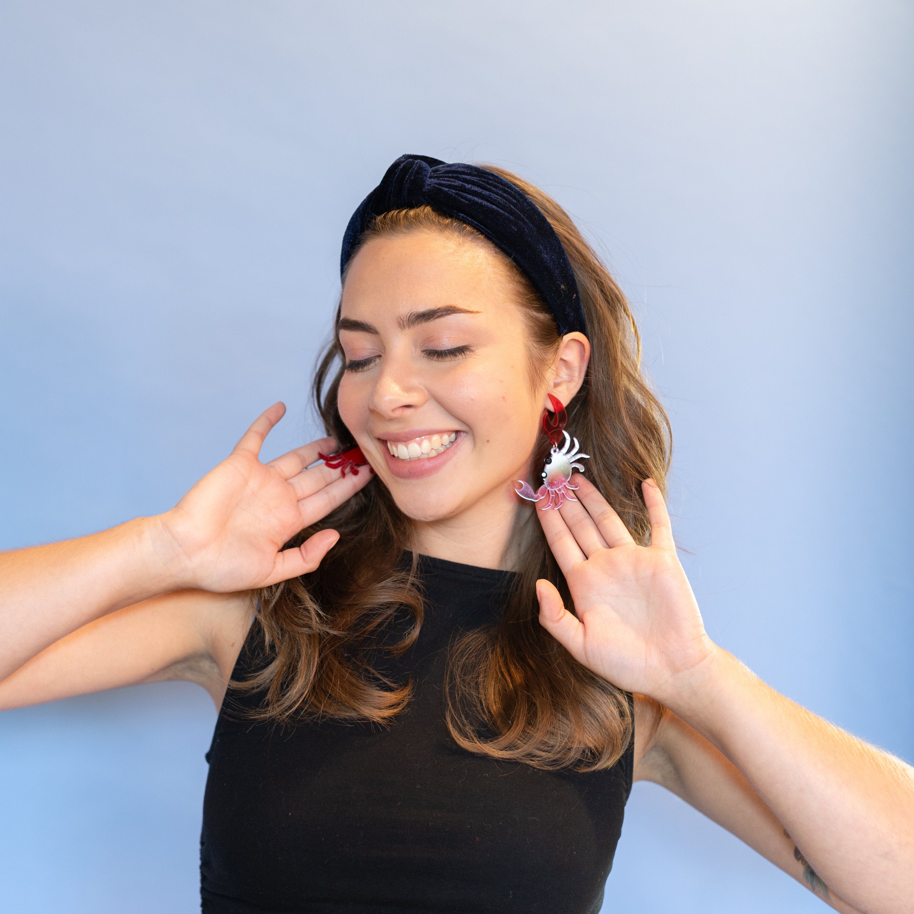 Woman wearing a black top and floral earrings against a light blue background
