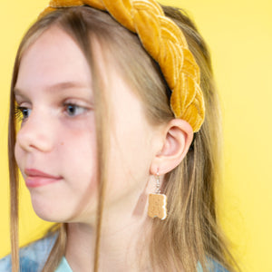 Girl wearing a yellow headband and blue tie-dye shirt against a yellow background