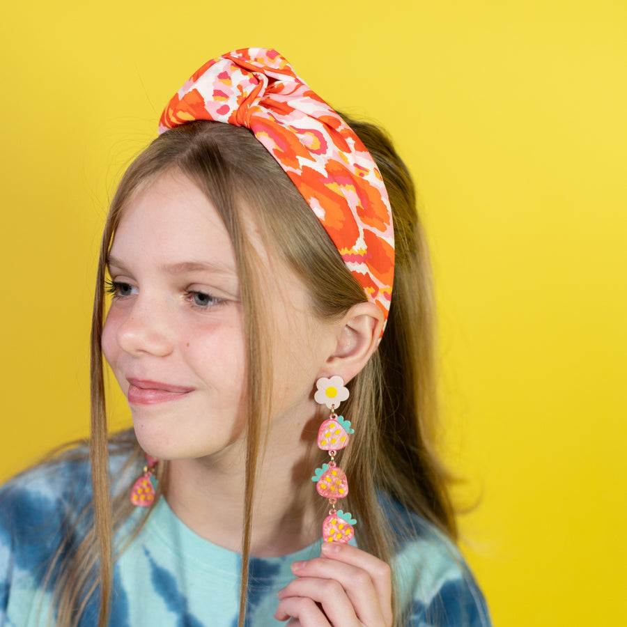 Woman wearing a black top and floral headband with earrings on a white background