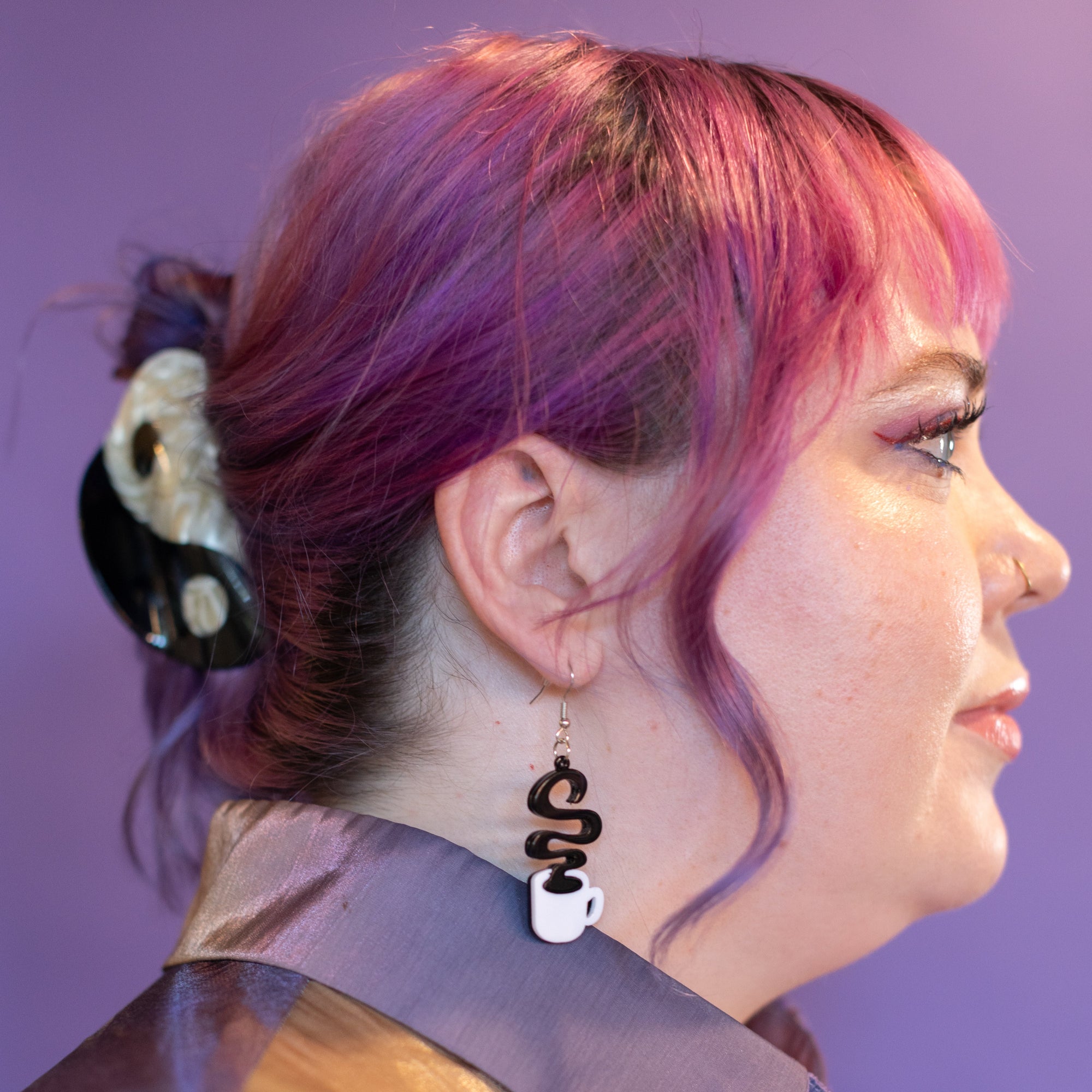 Person with pink hair and a purple background