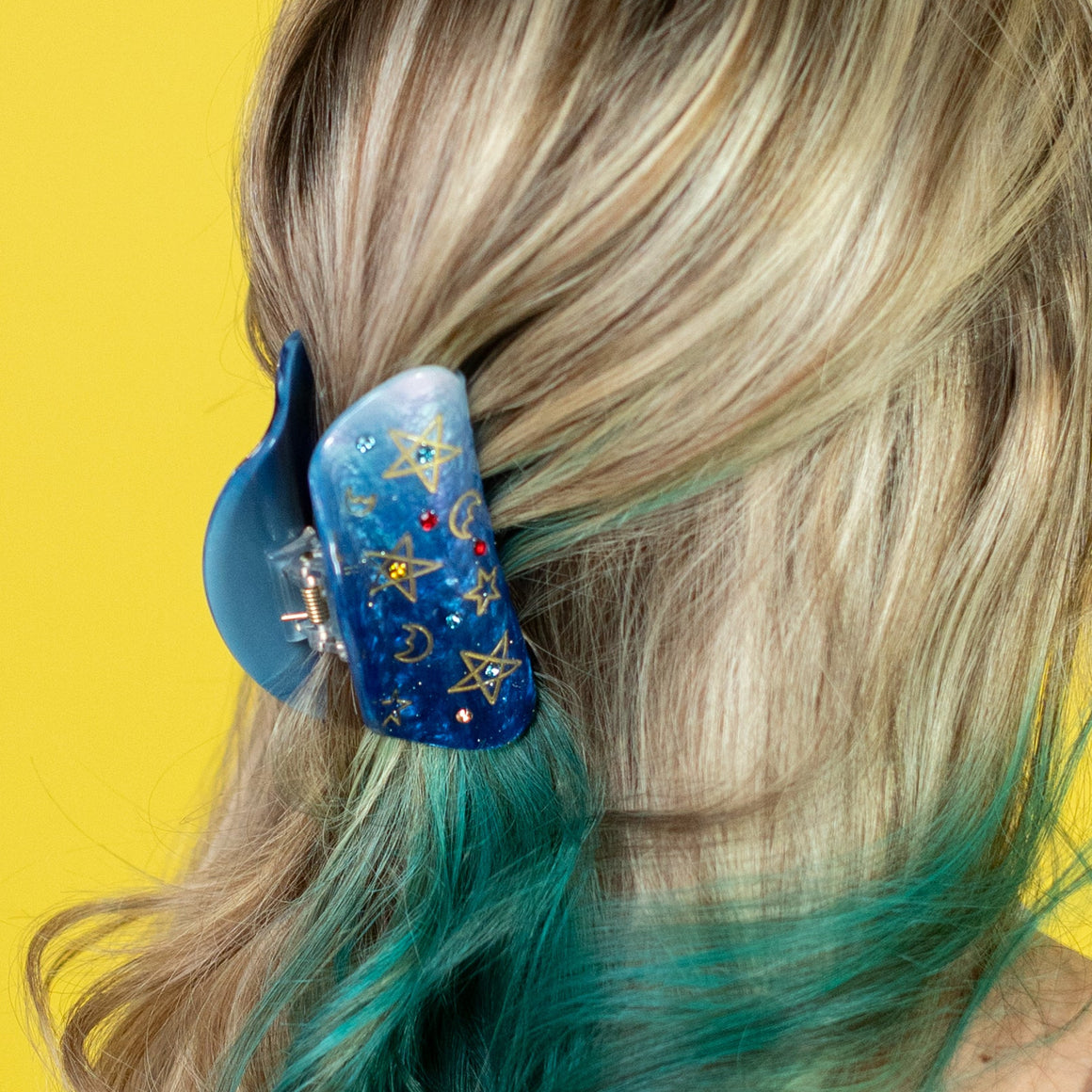 Woman with teal and blonde hair against a yellow background