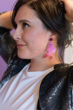 Woman wearing pink earrings with a blurred background