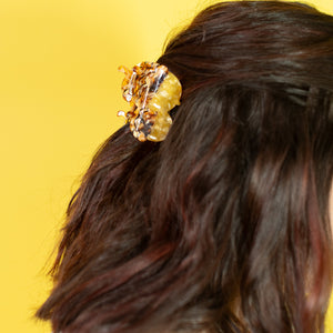 Close-up of a person's hair with a decorative hair clip against a yellow background