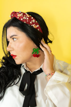 Woman wearing a decorative headband, earrings, and a white blouse with a yellow background