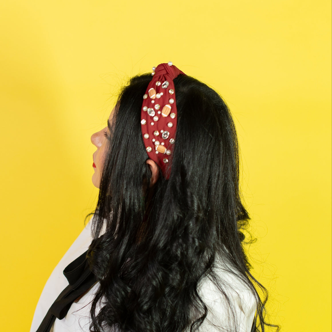 Person with long black hair wearing a white shirt and black pants against a yellow background