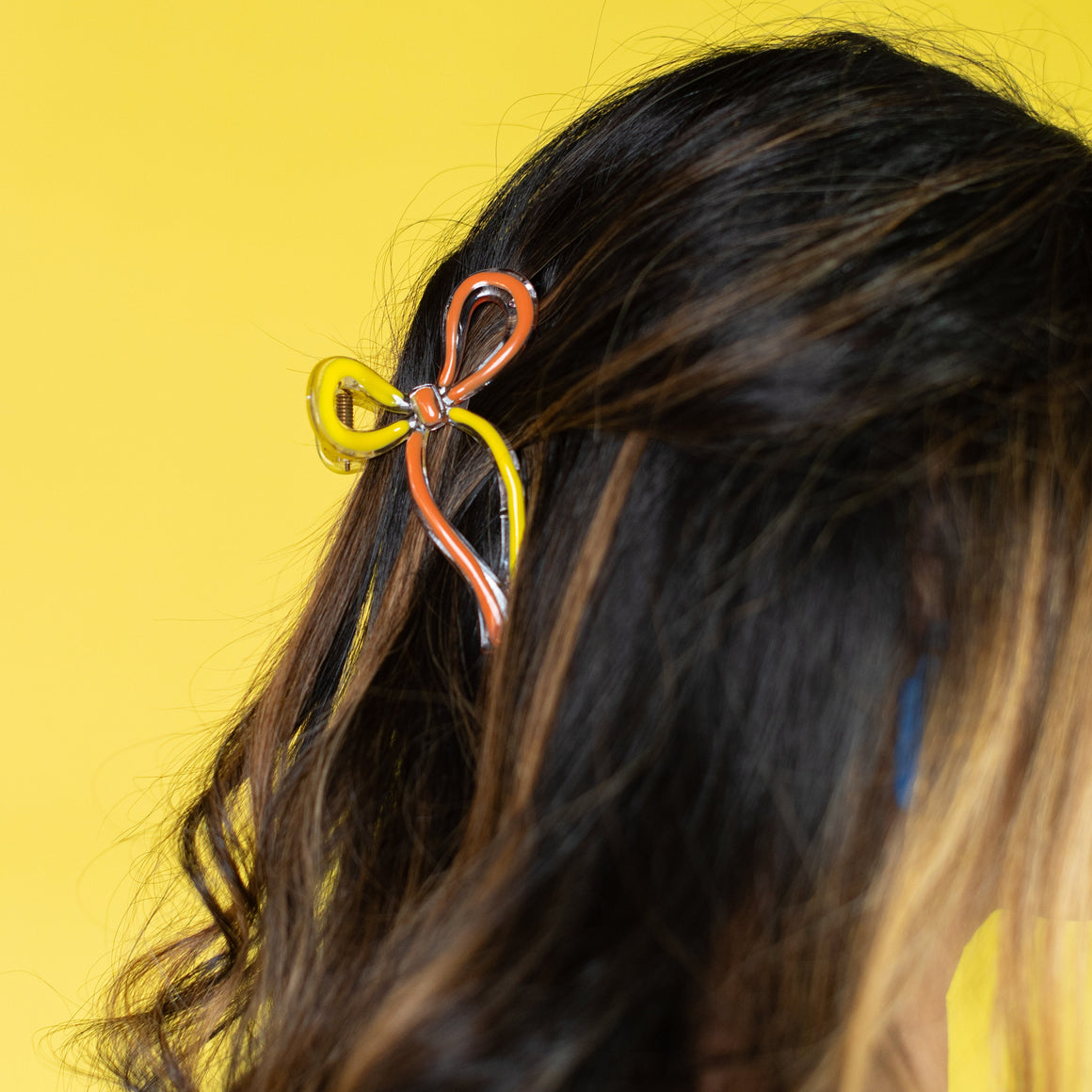 Person with a colorful hair tie in their hair against a pink background