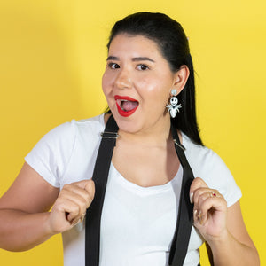 Woman wearing a white shirt and black suspenders against a yellow background