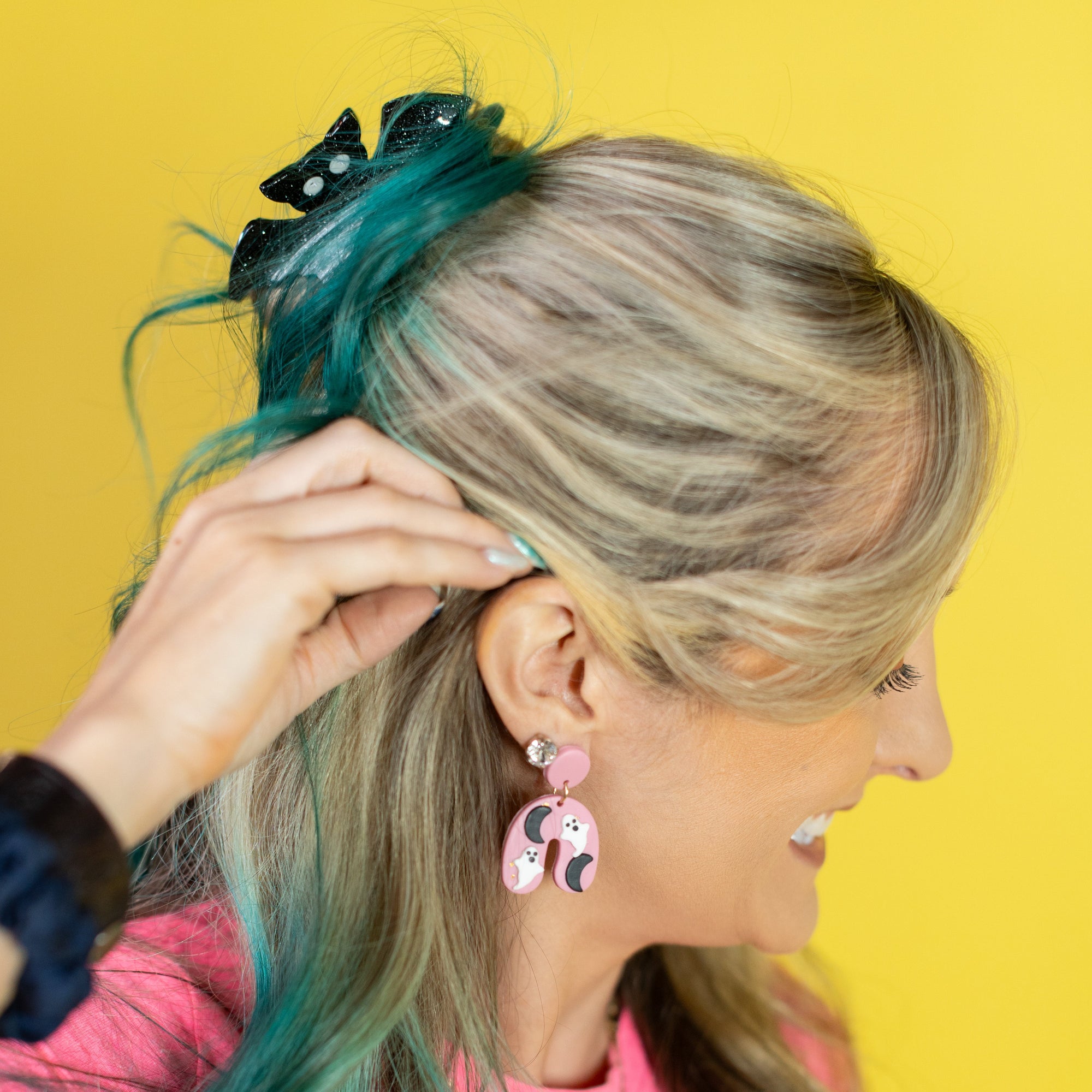 Woman with green hair and pink top against a yellow background