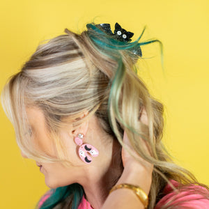 Woman with pink hair and accessories against a yellow background