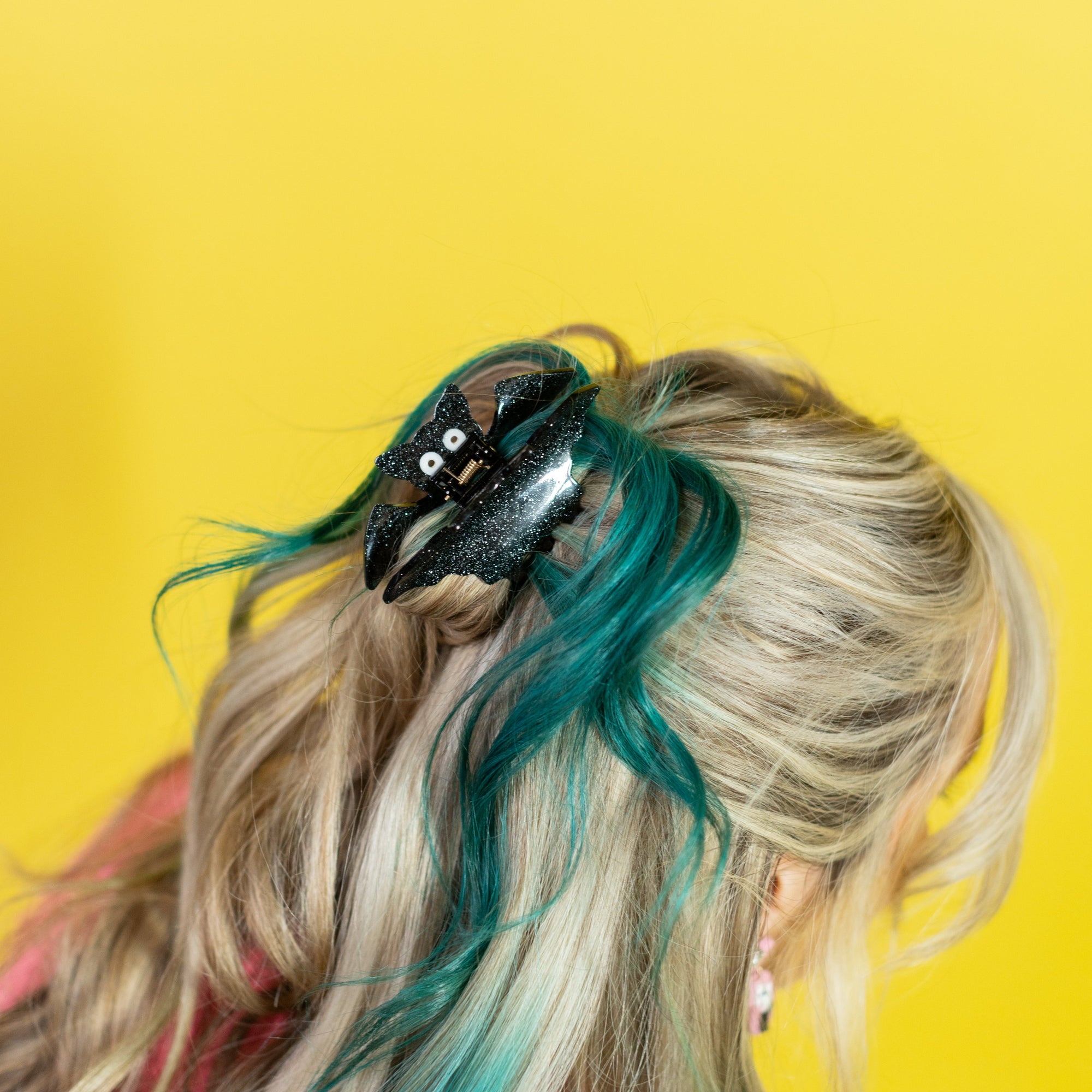 Person with colorful hair and a hair accessory against a yellow background