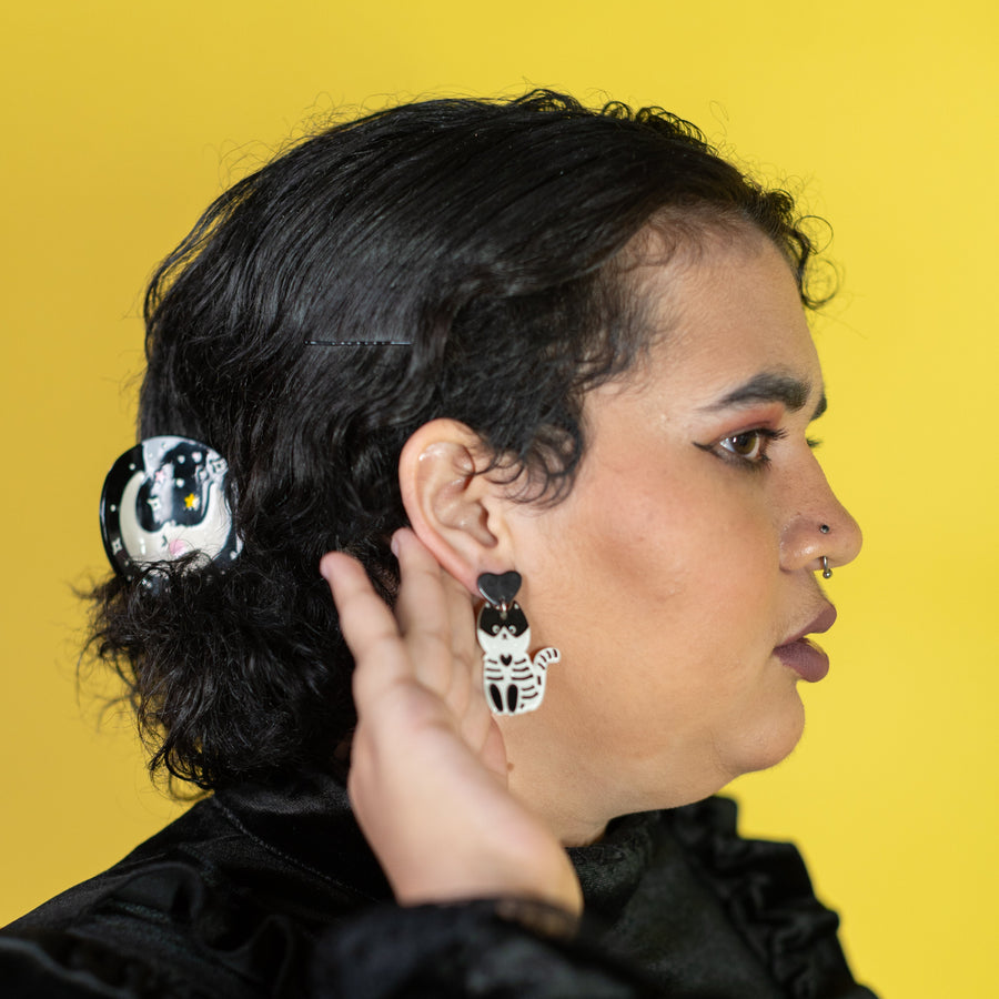 Person wearing a hair clip with a cat design against a yellow background