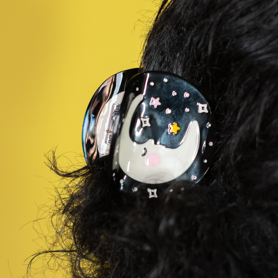 Person wearing a hair clip with a cat design against a yellow background