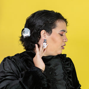 Person wearing a black outfit with ruffled details against a yellow background