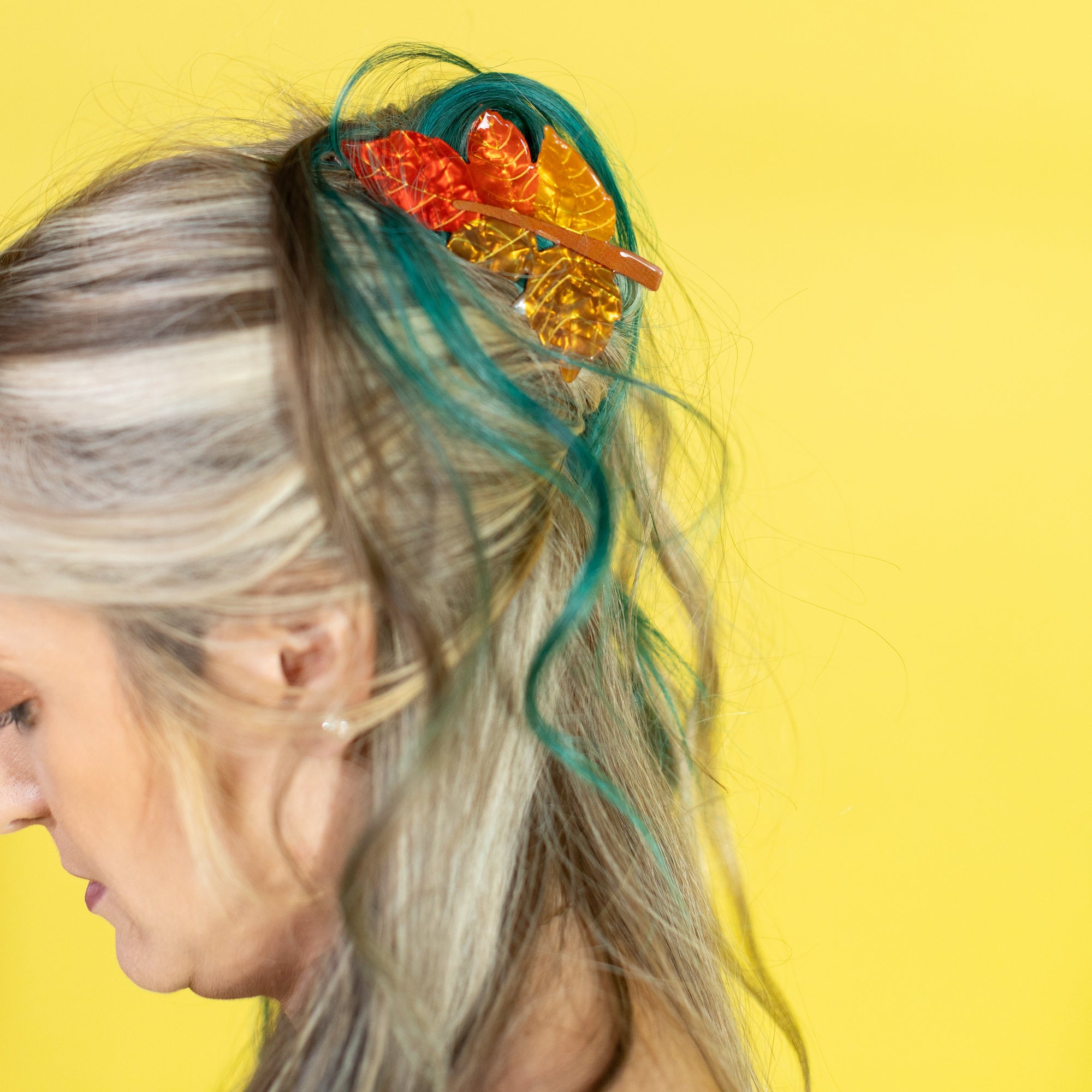 Person with colorful hair accessory against a yellow background