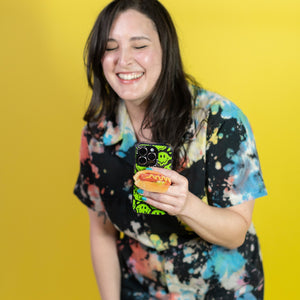 Person wearing a colorful outfit holding a phone with a yellow background