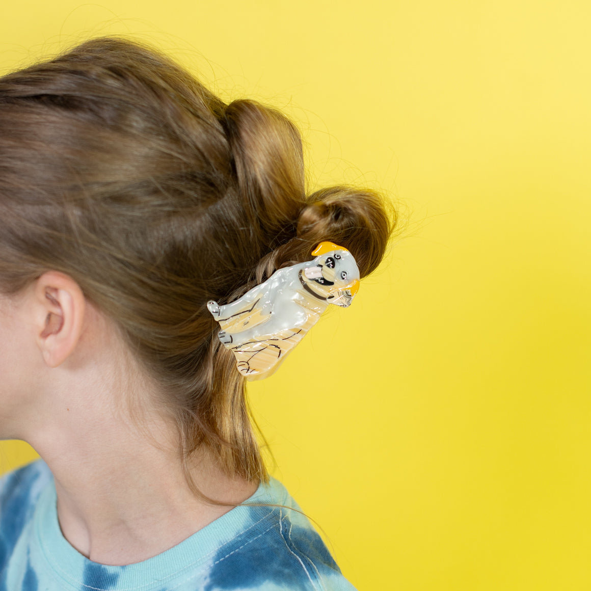 Person with a hair clip shaped like a dog on a yellow background