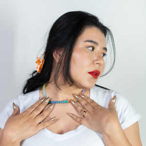 Woman wearing a white top with a black belt against a plain background
