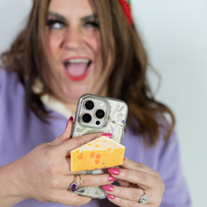 Person holding a phone with a colorful case against a plain background