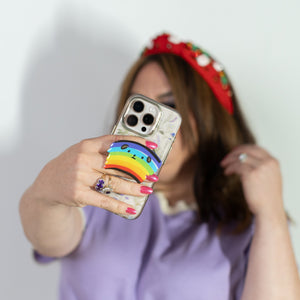 Person holding a phone with a colorful case against a plain background