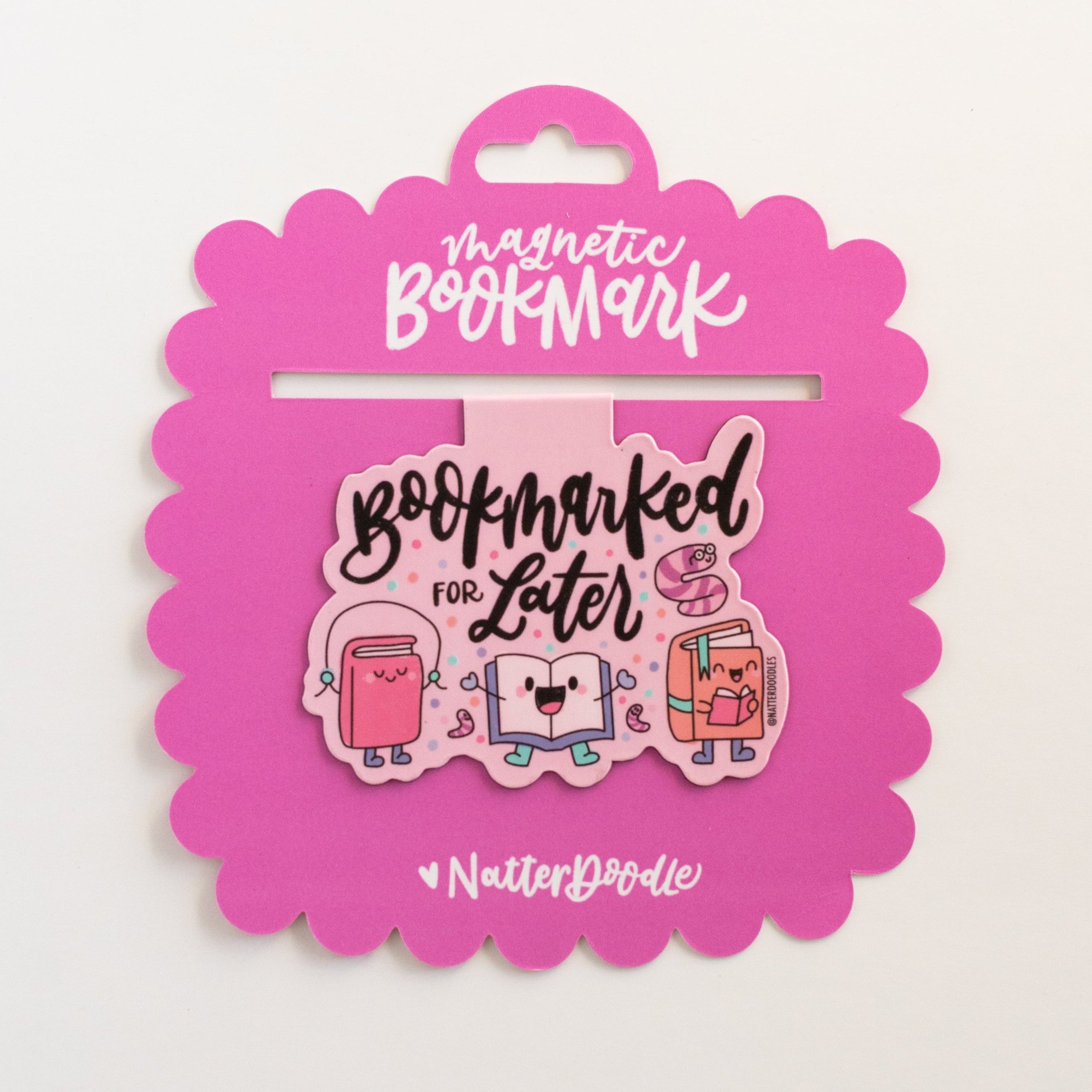 Pink packaging with a bookmark featuring cartoon cats and text on a white background