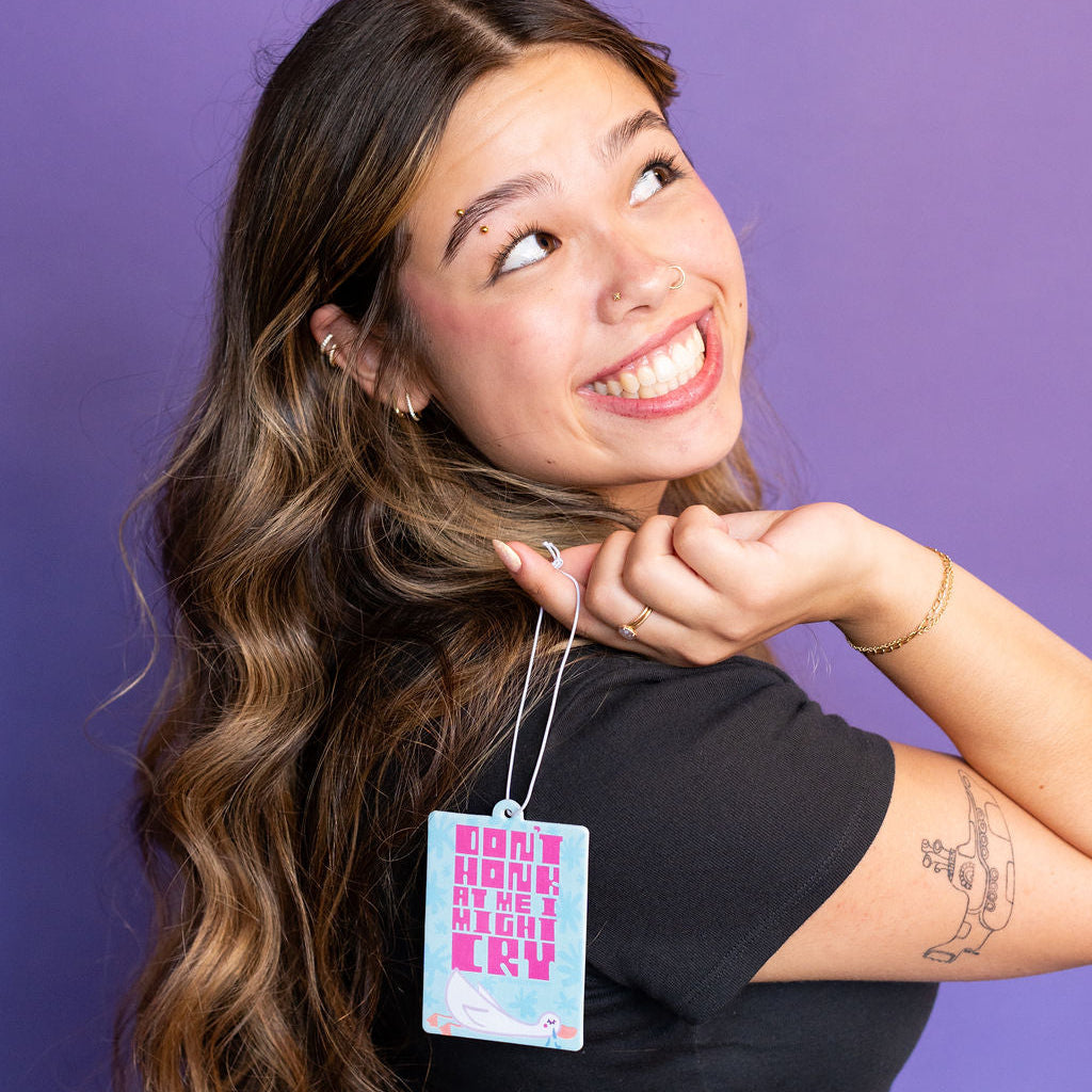 girl holding a blue car air freshener over her shoulder