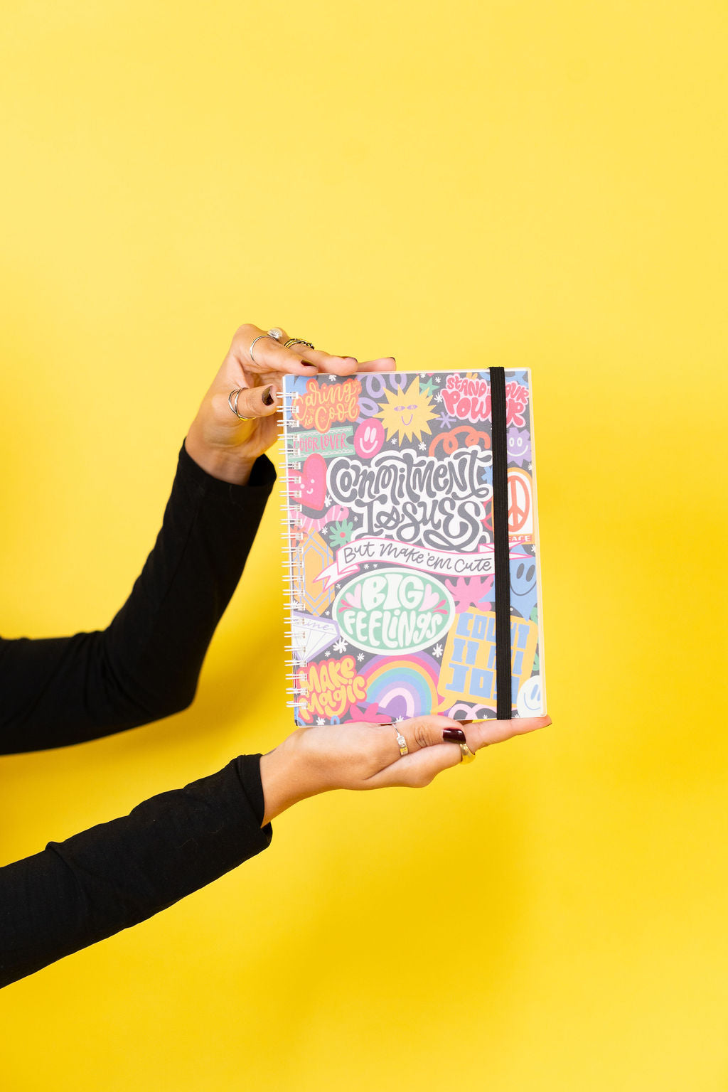Person holding a colorful notebook with text on a yellow background