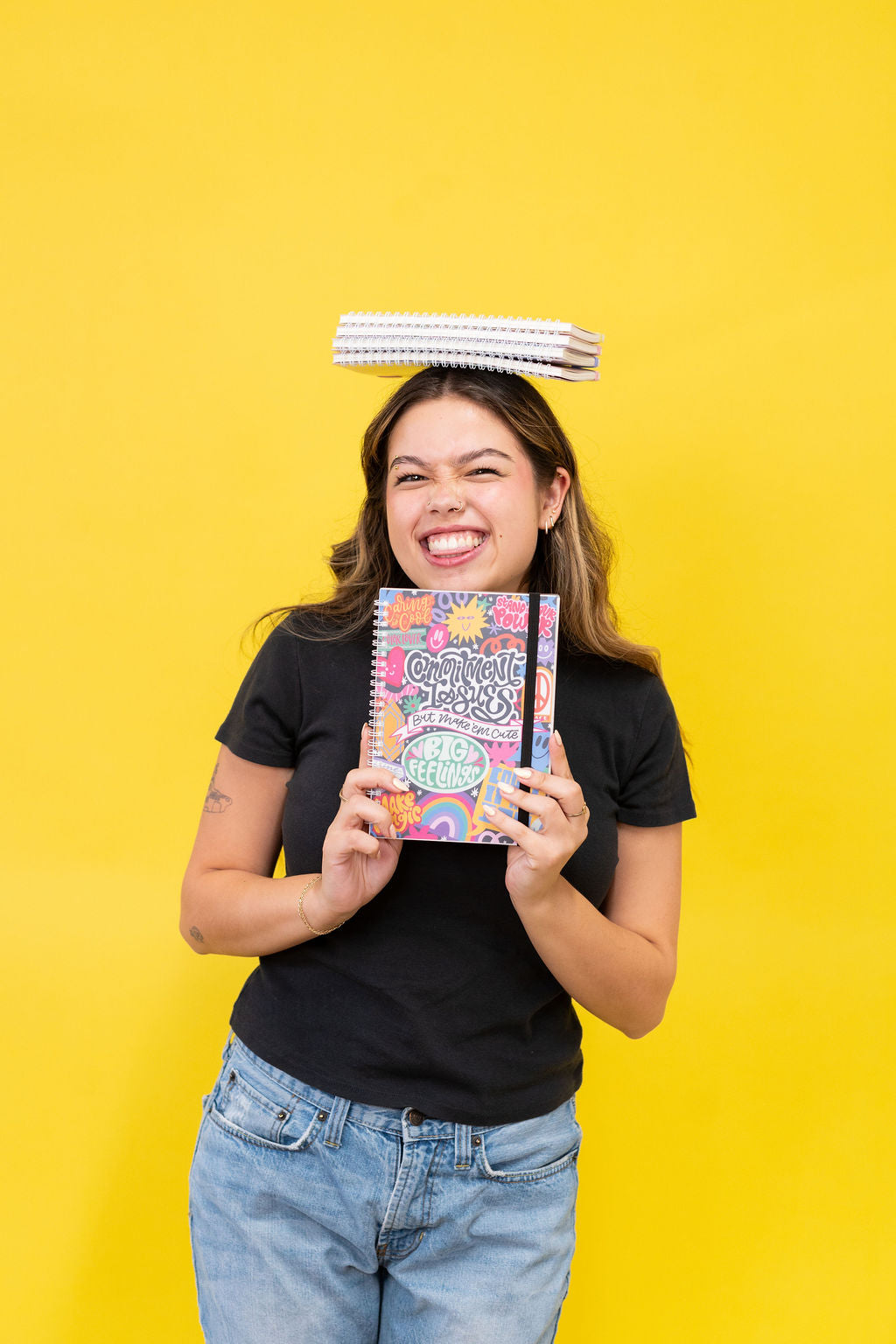 Person holding a colorful notebook with a yellow background