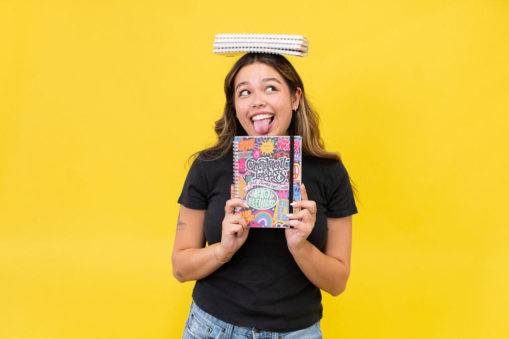 Woman holding a book with a colorful cover against a yellow background