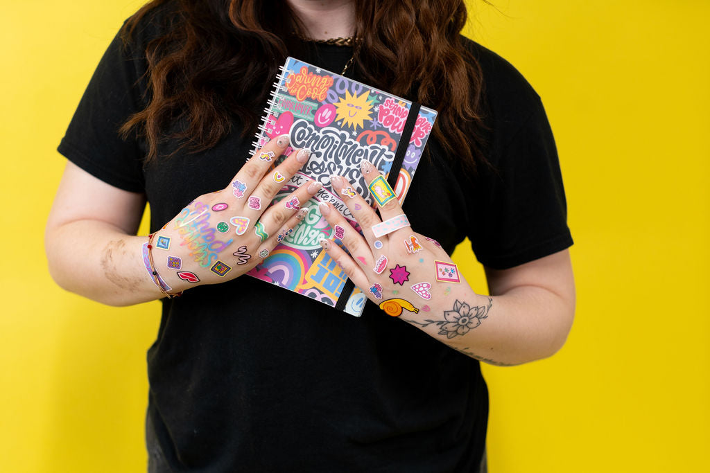 Person holding two colorful notebooks with a yellow background