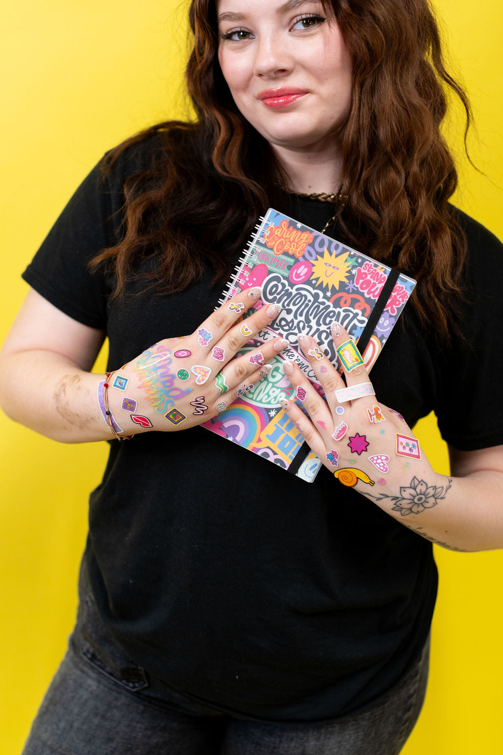 Person holding colorful notebooks with a yellow background