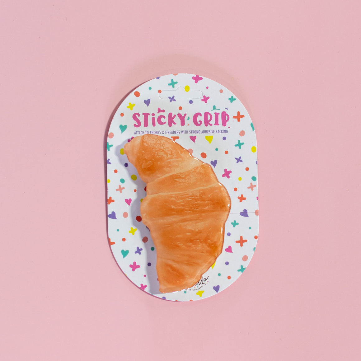 Sticky grip product with a croissant-shaped adhesive on a pink background