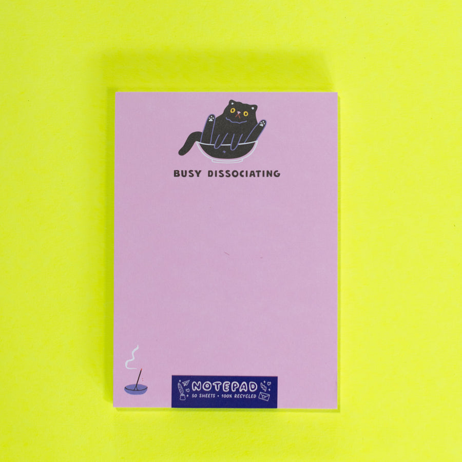 Pink notepad with a black cat illustration and text on a white background