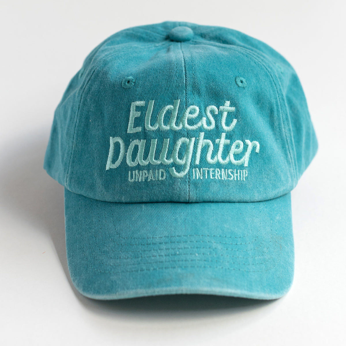 Eldest Daughter Unpaid Internship teal washed cotton dad cap with mint embroidered lettering, front view