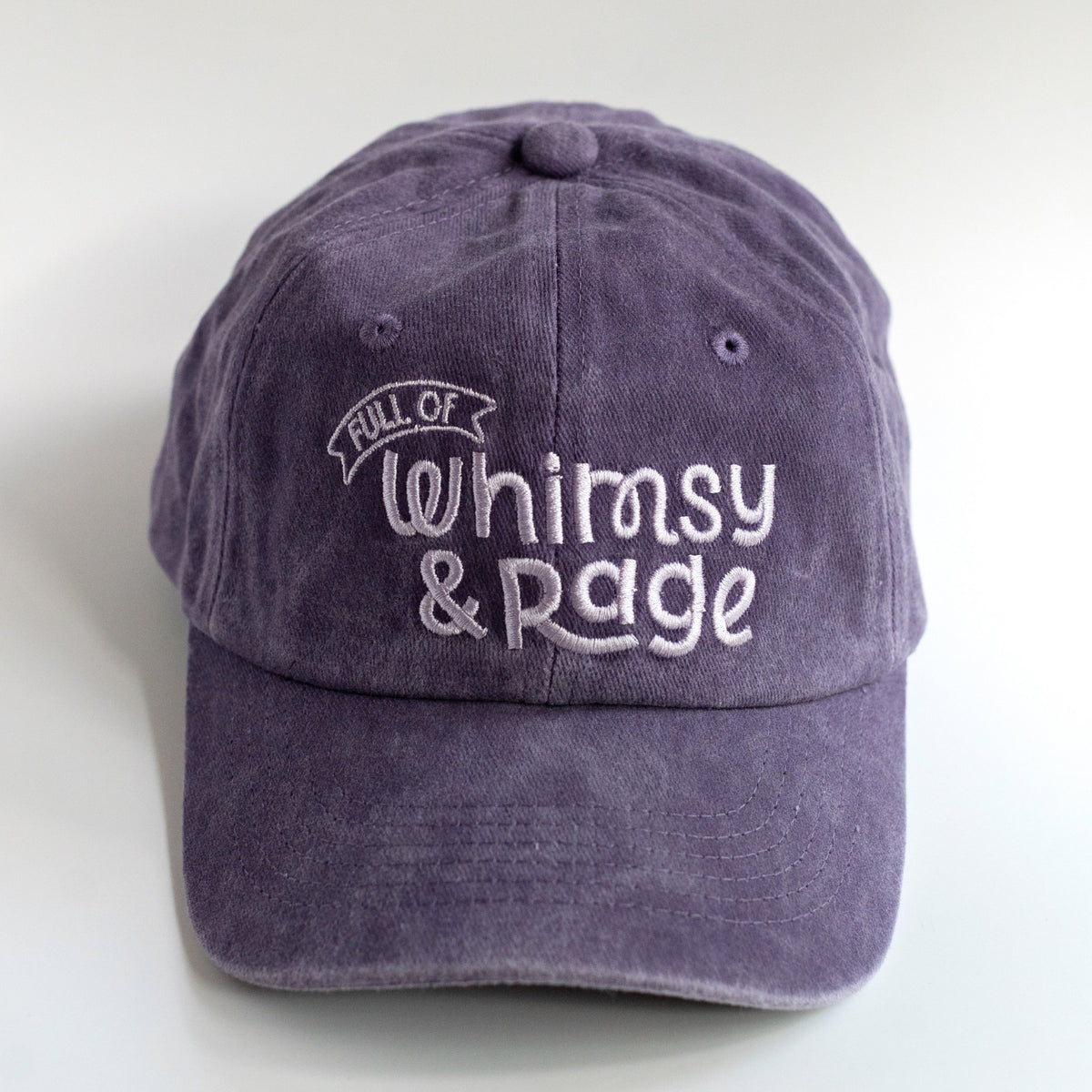 Front of washed purple dad hat with soft lavender Full of Whimsy & Rage embroidery and banner detail
