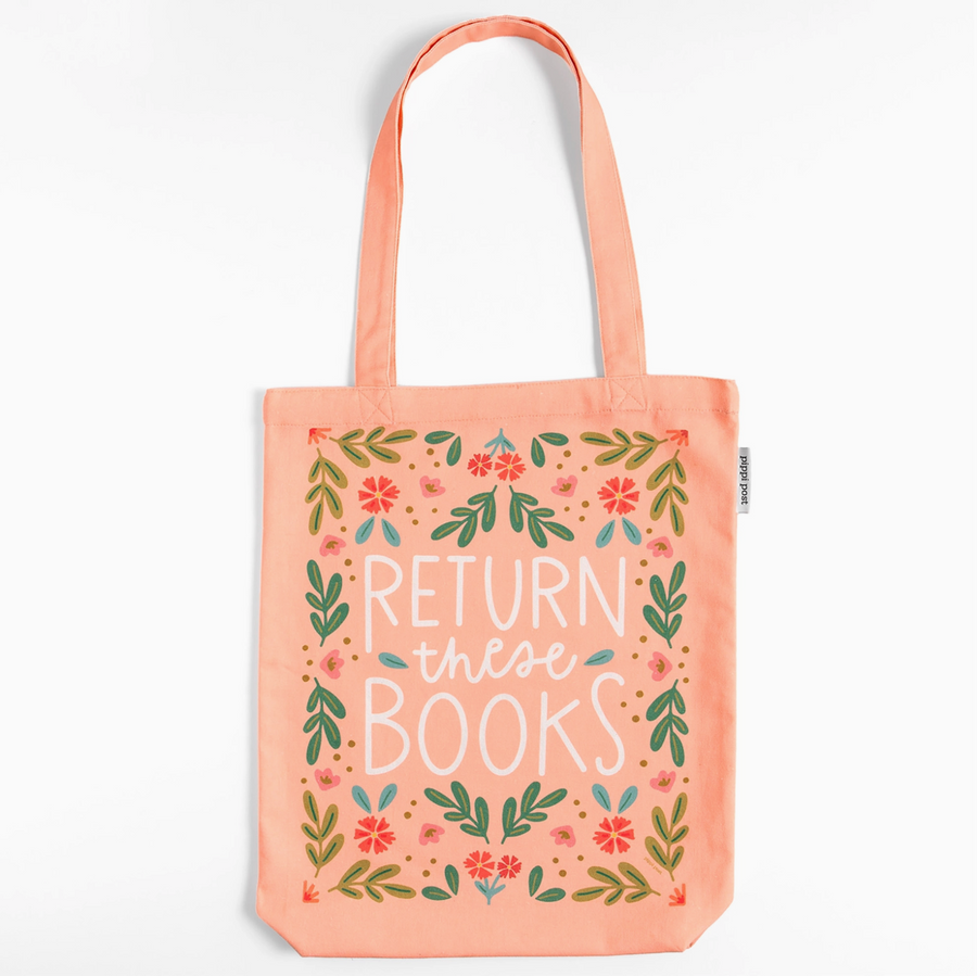 Pink tote bag with 'RETURN these BOOKS' text and floral designs on a light surface with books.