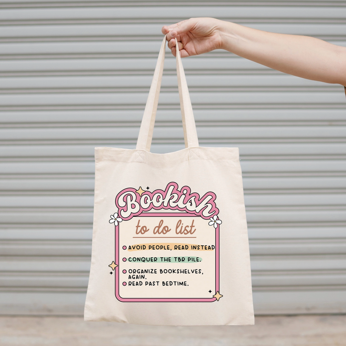 Tote bag with 'Bookish to do list' design held by a hand against a neutral background