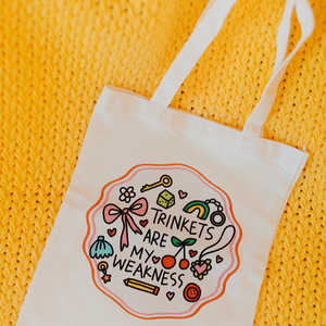 White tote bag with decorative text and illustrations on a yellow textured background