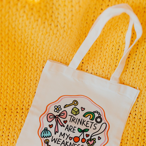 White tote bag with decorative design and text on a yellow textured background