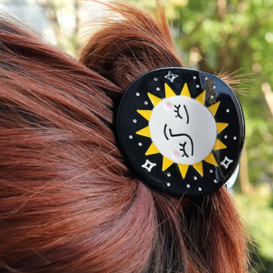 Person with a hair clip featuring a sun design against a yellow background